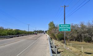 Women Hollaring Creek sign